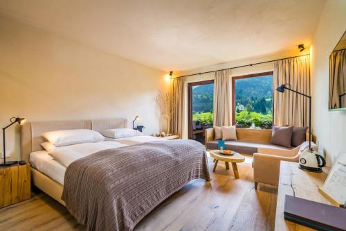 una camera con un grande letto e un divano di Posthotel Achenkirch Resort and Spa - Adults Only ad Achenkirch