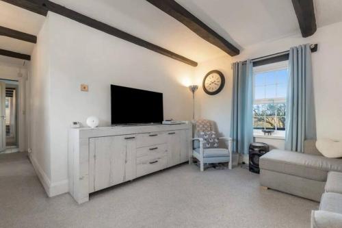a living room with a flat screen tv and a couch at Foxen Holes Cottage in Saundersfoot