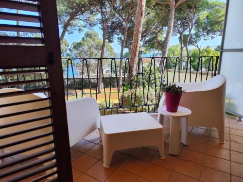 uma varanda com cadeiras, uma mesa e um banco em Apartamento con VISTAS AL MAR y jardín a 150 metros de la playa em Sant Antoni de Calonge