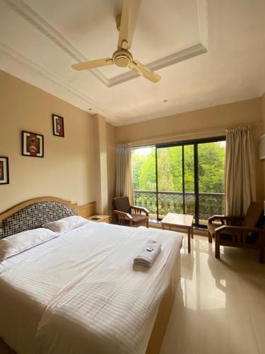 a bedroom with a large bed with a ceiling fan at Jewel Resort in Lonavala