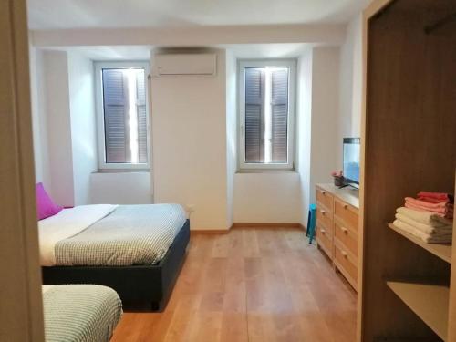 a bedroom with two beds and a dresser and two windows at lucia haus trieste in Trieste