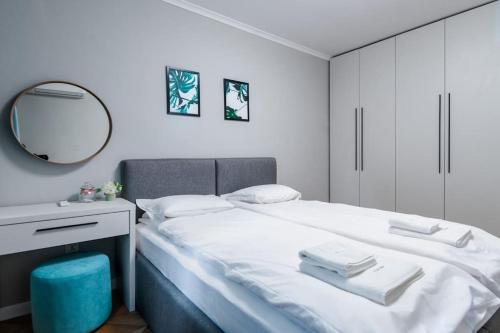 a white bedroom with a bed and a mirror at Lozenets Apartment in Sofia
