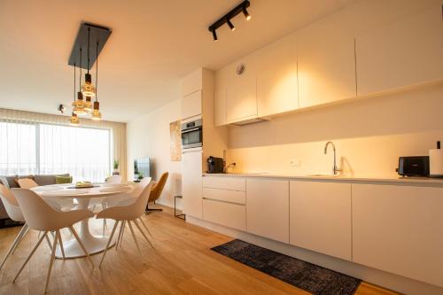 een keuken en eetkamer met een tafel en stoelen bij Modern en gezellig appartement vlak aan het strand in Blankenberge