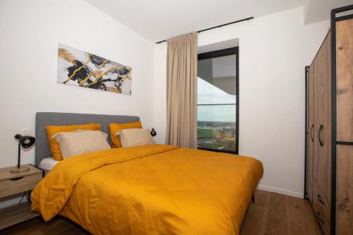 a bedroom with a yellow bed and a window at Modern en gezellig appartement vlak aan het strand in Blankenberge