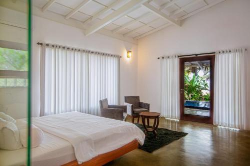 a bedroom with a bed and a chair and a window at Sri Lanka Beach House Hotel and SPA in Hikkaduwa