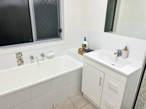 a white bathroom with two sinks and a bath tub at Stay at Chi’s in Kingston