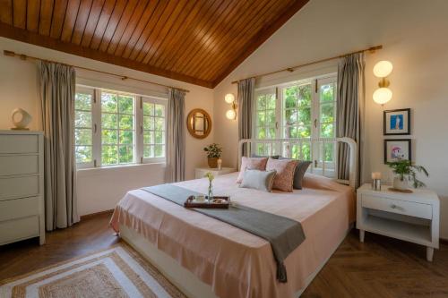 Un dormitorio con una cama grande con ventanas. en LohonoStays Ivy Cottage, en Dehradun