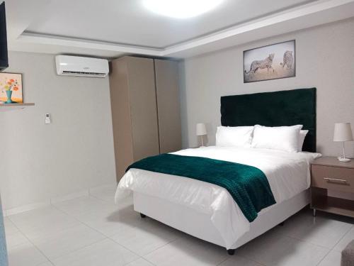um quarto com uma cama grande e um cobertor verde em CyC Guest Lodge em Giyani