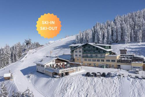 a ski lodge on a snow covered mountain with people on the roof at Hotel-Restaurant Planaihof in Schladming