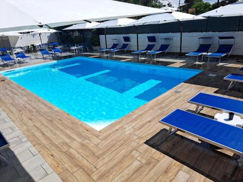 a large swimming pool with blue chairs and umbrellas at Le Pinède in Licola