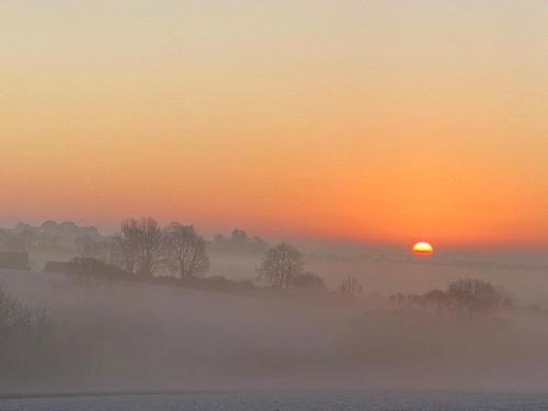 a misty sunrise with the sun in the horizon at Bedport Loft in Burrington