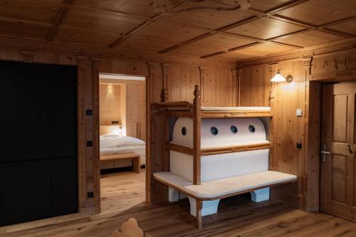 a cabin with a bed and a room with wooden walls at ALMA mountain residence in Dobbiaco