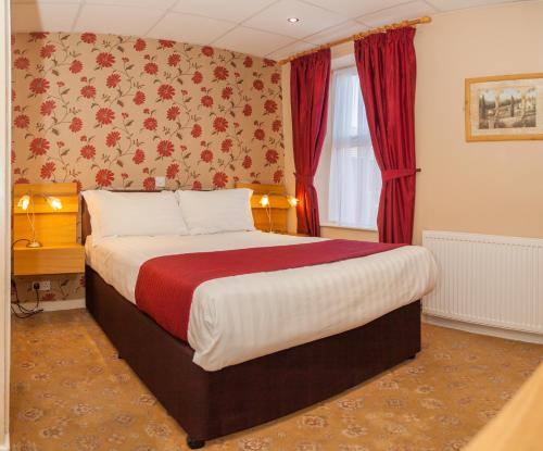 a bedroom with a large bed with red curtains at The Lawton in Blackpool