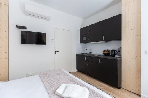 Cet appartement comprend une chambre avec un lit et une cuisine avec des placards noirs. dans l'établissement Le Colette - Joli studio en plein centre, à Bordeaux