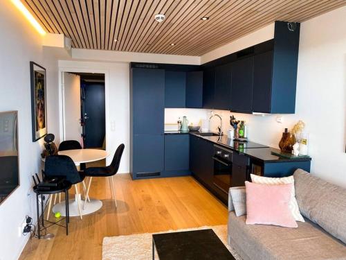 a living room with a couch and a kitchen with blue cabinets at Lovely and exclusive northern lights apartment with excellent view. in Tromsø