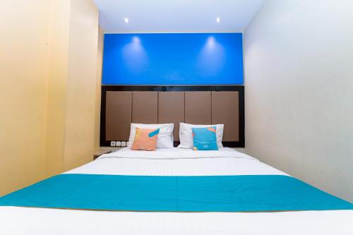 a bedroom with a large bed with a blue wall at Sans Hotel Liv Ancol by RedDoorz in Jakarta