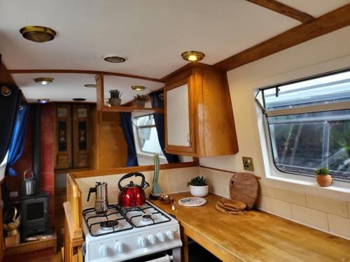 a kitchen with a stove and a tea kettle on a counter at Cosy Canal Boat in London Centre for Family & Friends in London