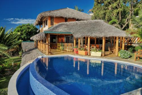a villa with a swimming pool in front of a house at VILLA PANORAMA NOSY BE in Nosy Be