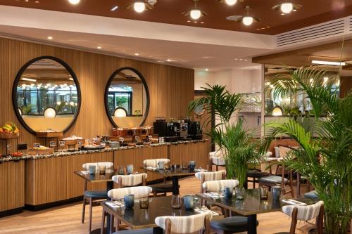 a restaurant with tables and chairs and a bar at Le Parchamp, a Tribute Portfolio Hotel, Paris Boulogne in Boulogne-Billancourt