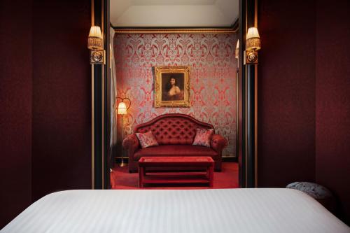a bedroom with a bed and a red chair at Maison Souquet, Hotel & Spa in Paris