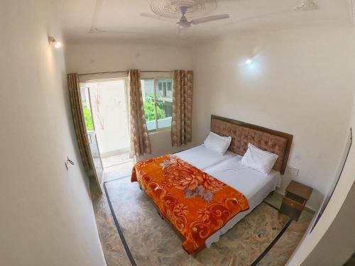 a bedroom with a bed with an orange blanket at Karma Hostel in Khajurāho