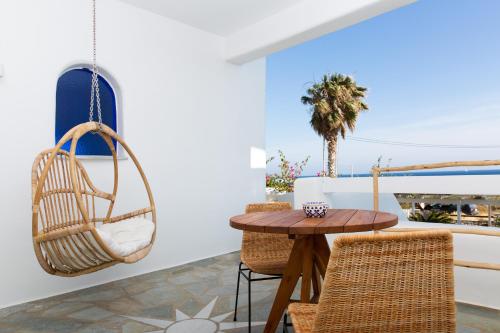 a room with a rattan swing and a table and chairs at KAMEO, Antiparos in Antiparos