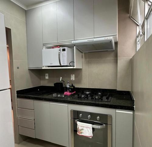a kitchen with white cabinets and a stove top oven at A tranquilidade está a seu alcance. in São Vicente