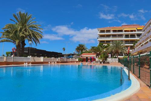 Una gran piscina con palmeras y un edificio. en Sunflower Apartment Just Relax, en Puerto de Santiago