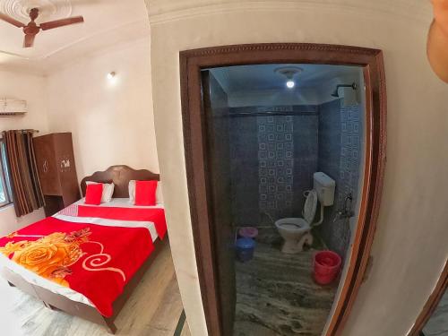 a bedroom with a bed and a bathroom with a toilet at Karma Hostel in Khajurāho