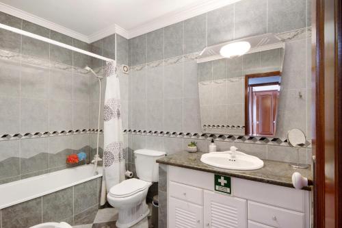a bathroom with a toilet and a sink and a mirror at Live Vagueira Beach in Praia da Vagueira