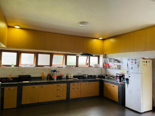 a kitchen with wooden cabinets and a white refrigerator at Martam Farmhouse in Pelling