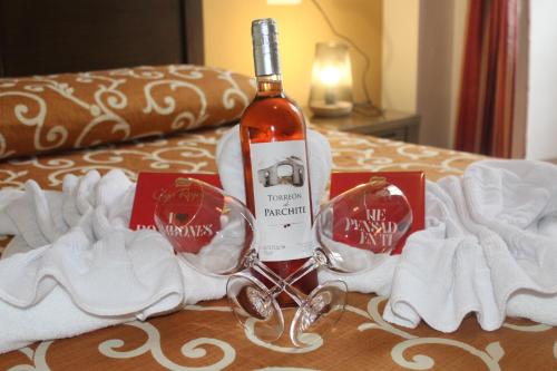 Hostal San Cayetano في روندا: زجاجة من النبيذ موضوعة فوق السرير