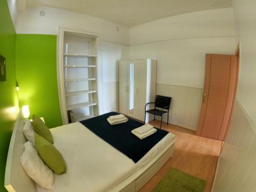 um quarto com uma cama com paredes verdes e uma cadeira em Lisbon T2 apartment in typical villa in Sapadores Lisbon em Lisboa