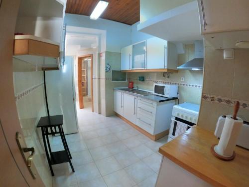 uma cozinha com armários brancos e um forno com placa de fogão em Lisbon T2 apartment in typical villa in Sapadores Lisbon em Lisboa