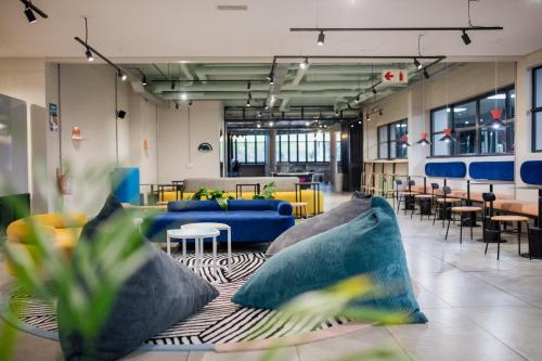 - un hall avec des canapés bleus, des tables et des chaises dans l'établissement CampusKey Cape Town, au Cap