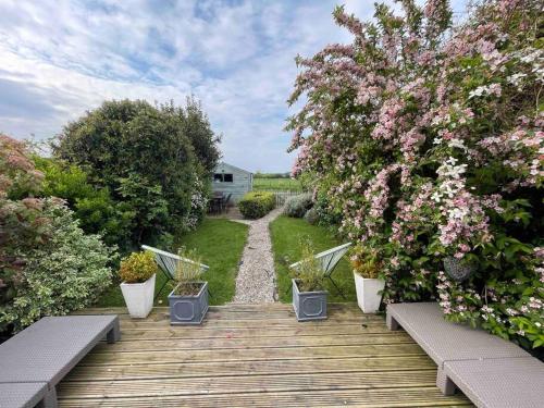 a wooden walkway with plants and flowers on it at Charming North Norfolk flint cottage in Baconsthorpe