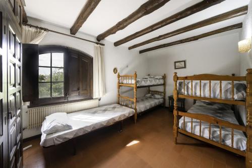 a bedroom with two bunk beds and a window at Can Mariné in San Antonio de Vilamajor