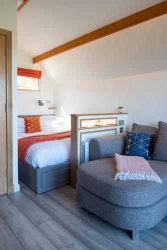 a bedroom with a bed and a couch and a chair at Bonnie Barns - Adults Only Luxury Lodges with hot tubs in Luss
