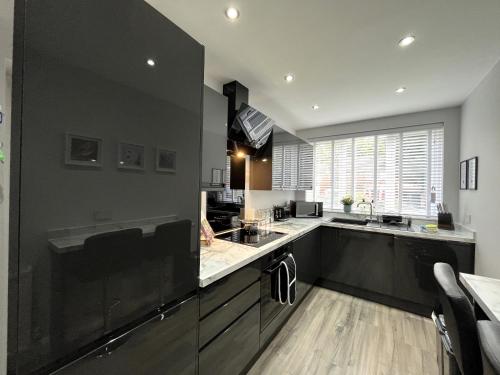 cocina grande con armarios negros y ventana grande en Modern 3-bed stay-away-home sleeps 6 nr Manchester, en Mánchester