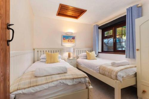 a bedroom with two beds and a window at Cornflower in Saundersfoot