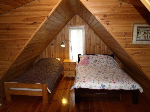a bedroom in a log cabin with a bed and a window at Holiday Home near Lake Mausz with Sauna in Kłodno