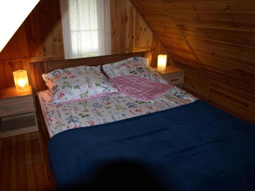 a bed in a wooden room with two lights at Holiday Home near Lake Mausz with Sauna in Kłodno