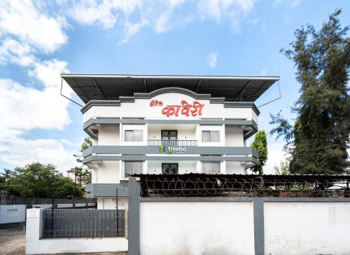 Ein weißes Gebäude mit einem roten Schild drauf. in der Unterkunft Treebo Trend Kaveri in Nashik