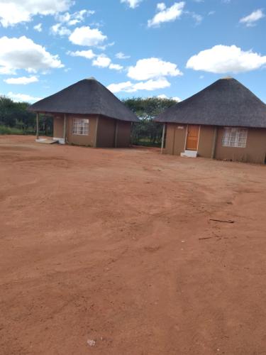 due case con tetti di paglia su un campo di terra di Pa Vula Hotels a Bokaa