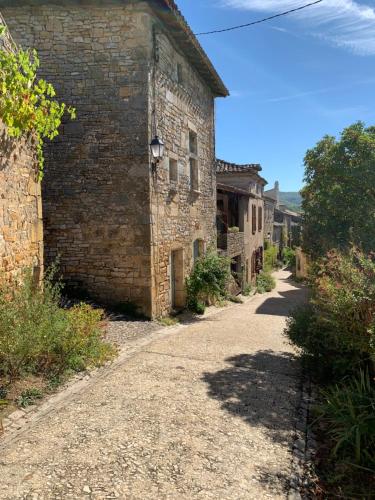 an old brick building with a road next to it at La Maison des Ecureuils - Bruniquel in Bruniquel