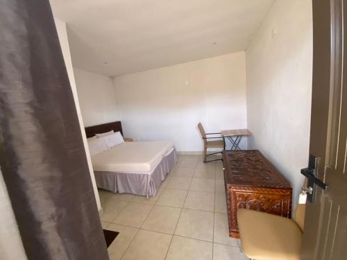 um pequeno quarto com uma cama e uma mesa em Aeropark Residencial(1) em Maputo