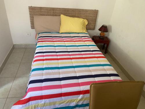 a bed with a colorful striped blanket on it at Aeropark Residencial(1) in Maputo