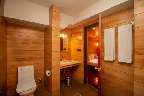 a bathroom with wooden walls and a toilet and a sink at NRS Norling Retreat in Darjeeling