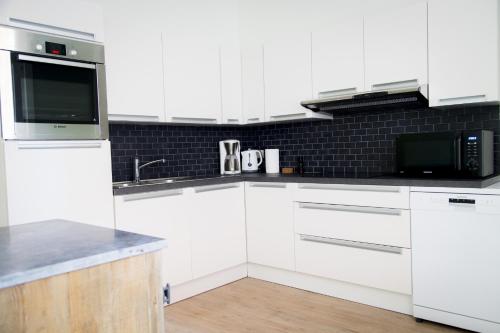 a white kitchen with white cabinets and a microwave at Two White Pigeons in Ypres