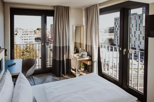 a hotel room with a bed and large windows at Emma by Schulz Hotel Berlin Friedrichshain in Berlin